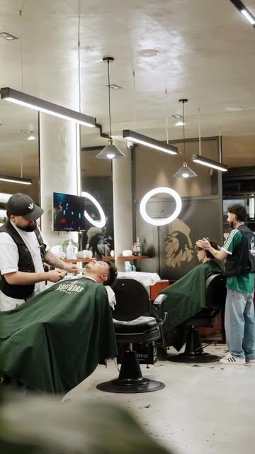 Barberos trabajando en el salón con capas verdes